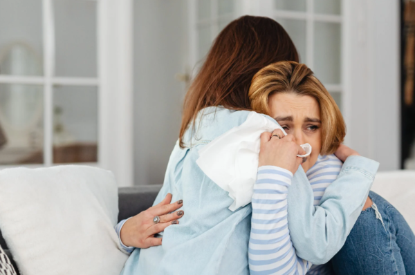 Woman hugging their friend in support as she has just had a miscarriage