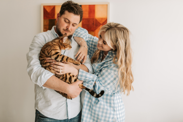 A couple holding their pet cat, preparing themselves to put their cat to sleep.